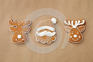 Christmas Santa Claus face and deer shaped gingerbread cookies on brown background, flat lay