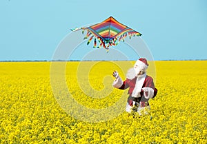 Christmas Santa Claus fling a kite in blooming yellow field.