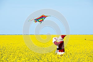 Christmas Santa Claus fling a kite in blooming yellow field. photo