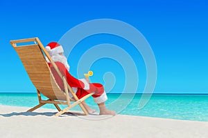 Christmas Santa Claus with fresh juice on sunlounger at tropical