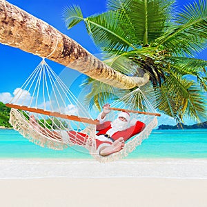 Christmas Santa Claus relax in hammock at tropical palm sandy ocean island beach