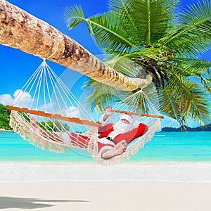 Christmas Santa Claus relax in palm shade hammock at tropical sandy ocean island beach