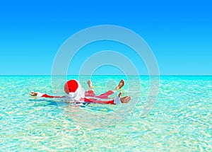 Christmas Santa Claus relax swimming in ocean turquoise transparent water.