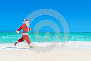 Christmas Santa Claus run at tropical beach against waves splash