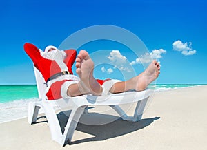 Christmas Santa Claus sunbathe on sunlounger at tropical ocean b