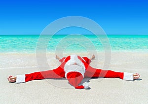 Christmas Santa Claus sunbathing at tropical ocean beach in wate