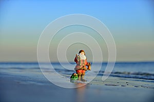 Christmas Santa Claus toy. Holiday and vacation concept. Winter on hot beach.
