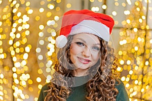 Christmas Santa Hat Woman Portrait. Smiling happy girl on bright bokeh