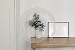 Christmas Scandinavian interior. Minimal winter artistic composition. Blank horizontal wooden picture frame mockup. Pine