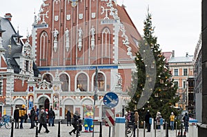 Christmas scene. Christmas tree on the square on the background of a beautiful building. People walking by. Riga. Latvia.