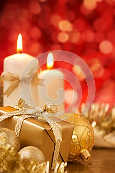 Christmas scene with gold baubles, gift and candles, red backgro