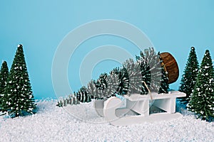 Christmas scene with pine tree forest, snow and sleigh carrying cutted tree on blue background