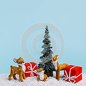 Christmas scene with red cup, pine tree, snow and small deer on pastel blue background. Creative Xmas or New Year festive concept.