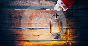 Christmas scene. Santa Claus hand holding vintage oil lamp
