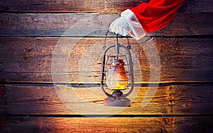 Christmas scene. Santa`s hand holding vintage oil lamp