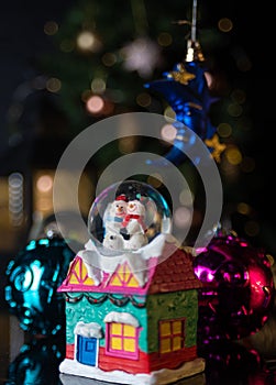 Christmas scene with tree, lights and snow globe. Selective focus on black background