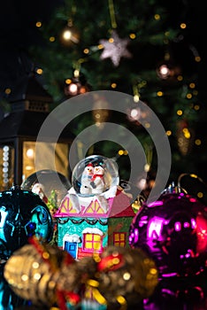 Christmas scene with tree, lights and snow globe. Selective focus on black background