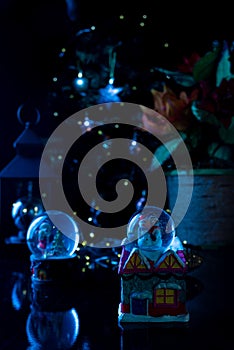 Christmas scene with tree, lights and snow globe. Selective focus on black background