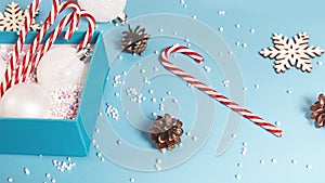 Christmas season border frame with candy canes and pine cones, gift box on pastel blue background. Creative New Year or Merry Xmas