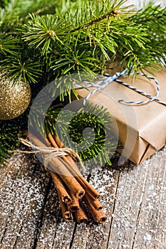 Christmas setting with bundle of cinnamon and pine branches on the rustic wooden background
