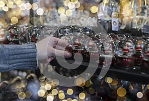 Christmas shopping concept. Hand choosing and buying xmas toys from shelf in store with santa clauses in glass spheres