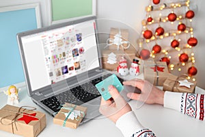 Christmas shopping online. Unrecognizable Man Hands holding Credit Card buying presents by using laptop.