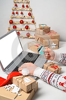 Christmas shopping online. Unrecognizable Man Hands holding Credit Card buying presents by using laptop.