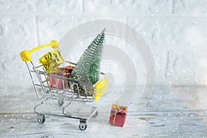 Christmas shopping season concept - mini shop cart trolley full of gift box on white brick background
