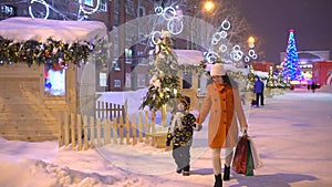 Christmas shopping. xmas. Christmas holiday shoppers at night, cross busy city street,slow motion Mother and her son