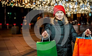 Christmas shopping of young beautiful woman. Colorful bright paper bags with gifts,presents.Walking on market street in city.