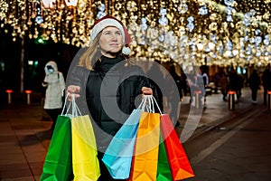 Christmas shopping of young beautiful woman. Colorful bright paper bags with gifts,presents.Walking on market street in city.