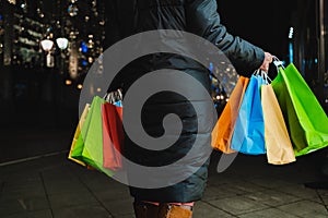 Christmas shopping of young beautiful woman. Colorful bright paper bags with gifts,presents.Walking on market street in city.