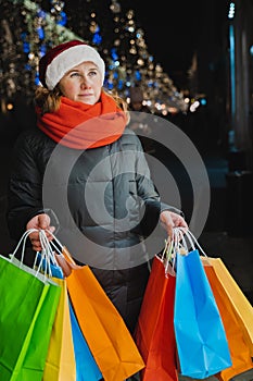 Christmas shopping of young beautiful woman. Colorful bright paper bags with gifts,presents.Walking on market street in city.