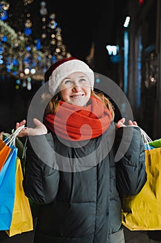 Christmas shopping of young beautiful woman. Colorful bright paper bags with gifts,presents.Walking on market street in city.