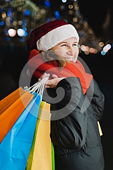 Christmas shopping of young beautiful woman. Colorful bright paper bags with gifts,presents.Walking on market street in city.