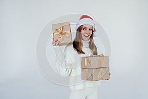 Christmas shopping young woman holding many gifts in her arms wearing santa hat