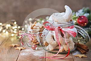 Christmas shortbread cookies crescents and stars with red ribbon, festive decoration, fir tree,balls and light garland.