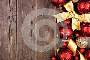 Christmas side border of red and gold ornaments and ribbon on a dark wood background