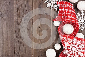 Christmas side border of red and white ribbon, baubles and snowflake decorations on a dark wood background
