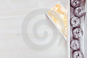 Christmas silver apples and lights burning in boxes on a wooden white background.