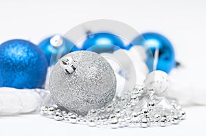 Christmas silver  ball in  focus and blue balls in background with ribbons and snow