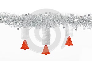 Christmas silver garland with red trees paper on white background.