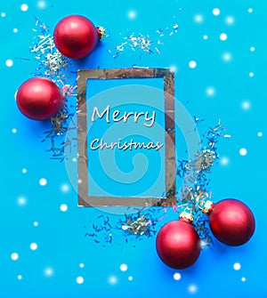 Christmas silver mockup frame and red baubles on bright blue background.