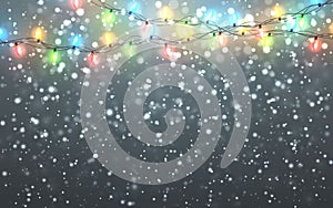 Christmas snow. Falling white snowflakes on dark background. Xmas Color garland, festive decorations. Glowing christmas lights.