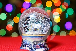 Christmas Snow Globe in front of Christmas tree lights closeup