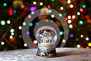 Christmas Snow Globe in front of Christmas tree lights closeup