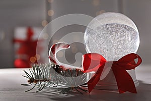 Christmas snow globe with red bow on table.