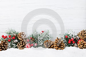 Christmas snow scene. Christmas tree branches with cones and ornaments on wooden light background,