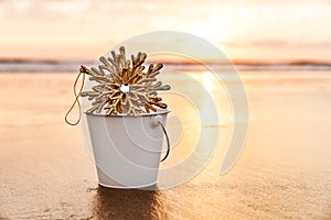 Christmas Snowflake in a White Bucket ar Sunset on the Beach in