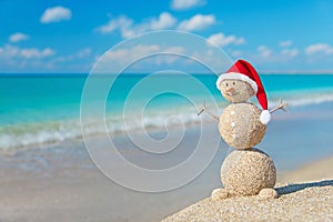 Christmas snowman in santa hat at tropical ocean beach